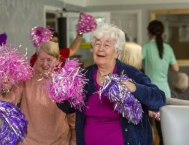 Residents at North Court care home dancing with pom poms - Maven Healthcare