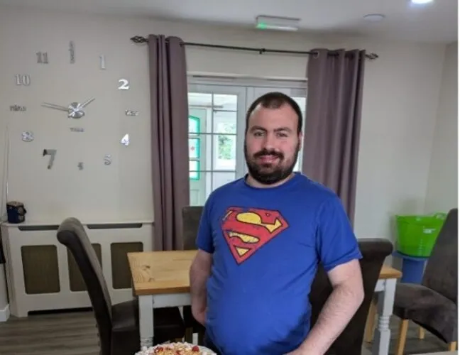 Resident at Inclusive Support care home stands next to a sweet treat - Maven Healthcare