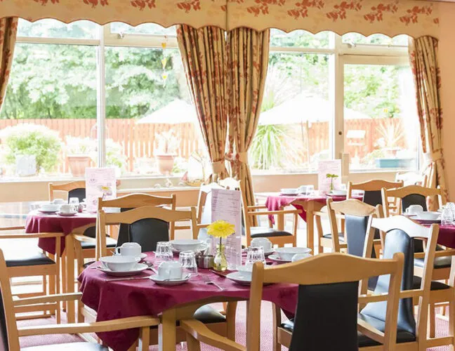 The dinner area with circular tables and chairs at Clyde Court care home in Clydebank - Maven Healthcare