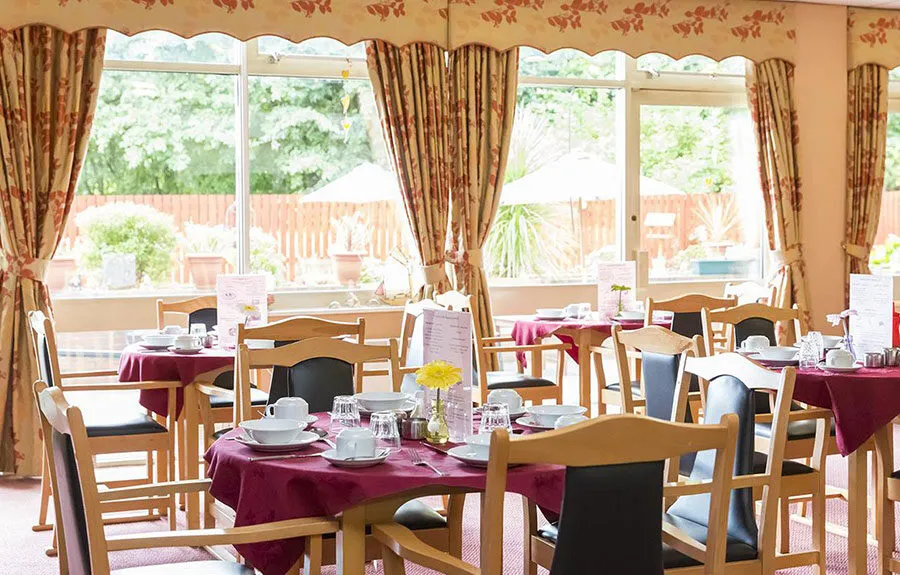 The dinner area with circular tables and chairs at Clyde Court care home in Clydebank - Maven Healthcare