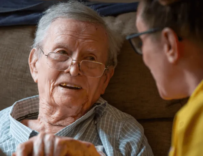 A member of staff talking to an elderly man in the care home - Maven Healthcare