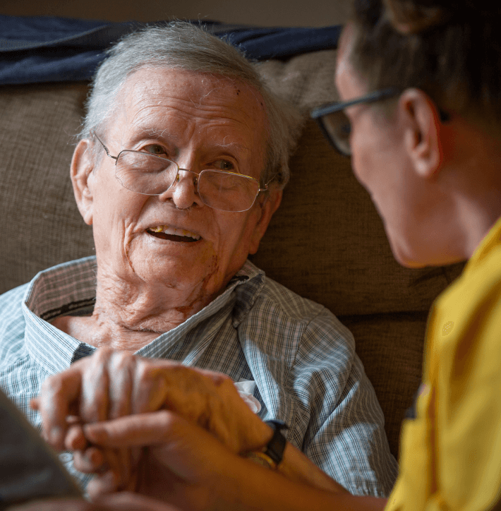 A member of staff talking to an elderly man in the care home - Maven Healthcare