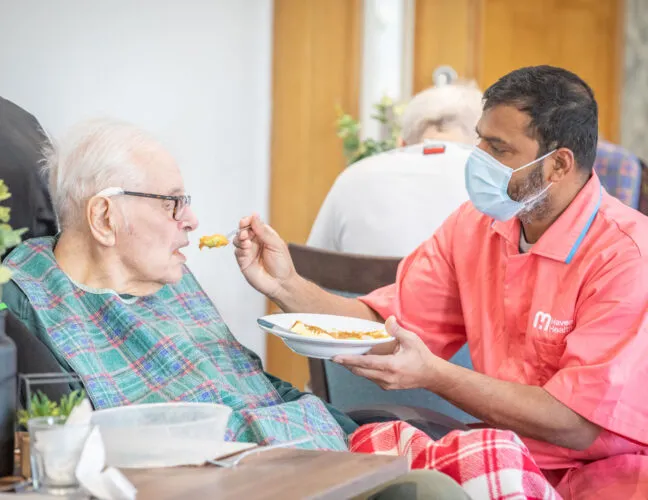 Nurse feeding an elderly resident at Midfield Lodge care home in Cambridge - Maven Healthcare